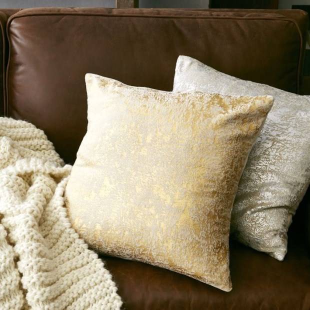 Блестящие подушки и вязанный плед для дивана